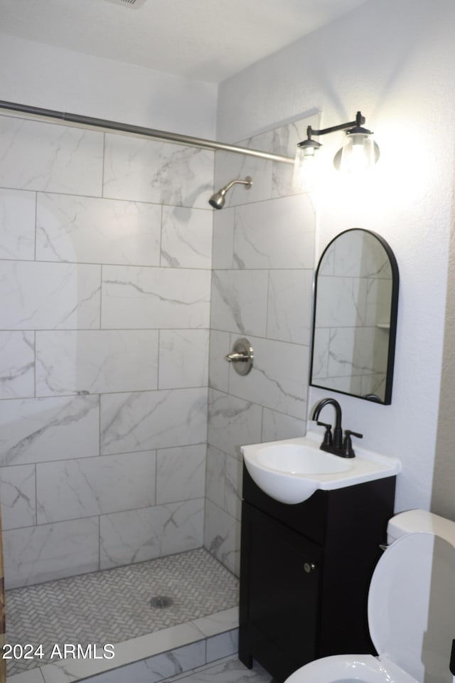 bathroom featuring a tile shower, vanity, and toilet