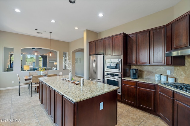 kitchen featuring decorative backsplash, light stone countertops, appliances with stainless steel finishes, decorative light fixtures, and a kitchen island