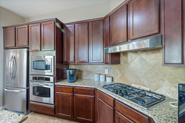 kitchen with light stone countertops, appliances with stainless steel finishes, backsplash, and light tile patterned floors