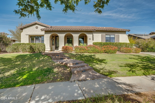 mediterranean / spanish house with covered porch and a front lawn