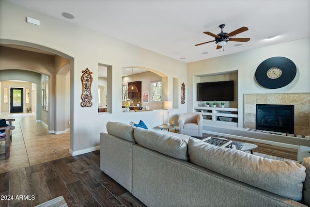 living room with a tile fireplace, dark hardwood / wood-style floors, plenty of natural light, and ceiling fan