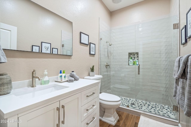 bathroom with hardwood / wood-style floors, vanity, toilet, and walk in shower