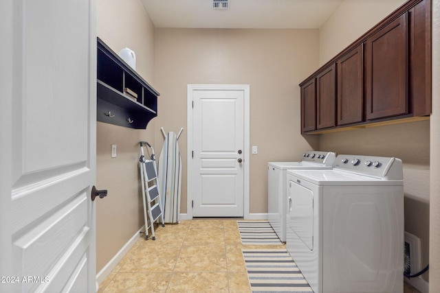 clothes washing area with cabinets, light tile patterned floors, and washer and dryer