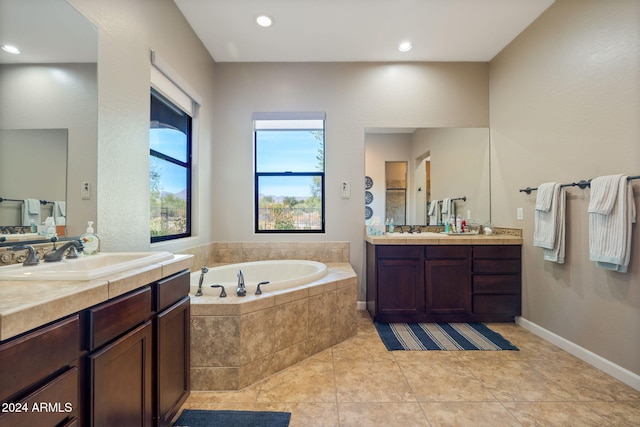 bathroom with tile patterned flooring, vanity, and tiled tub