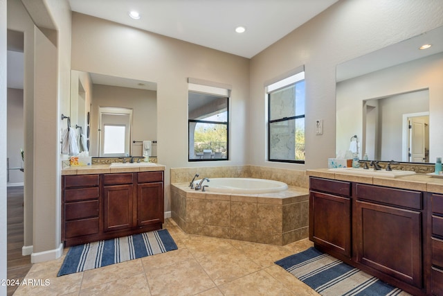 bathroom featuring tile patterned flooring, vanity, and tiled bath