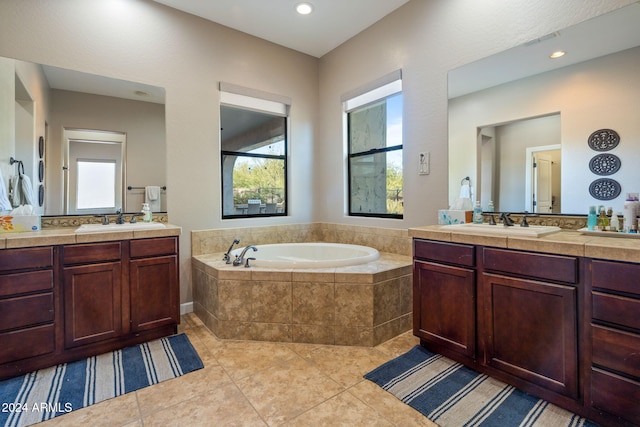 bathroom with tiled tub, tile patterned flooring, and vanity