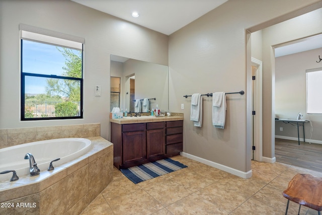 bathroom with tiled tub, tile patterned flooring, and vanity