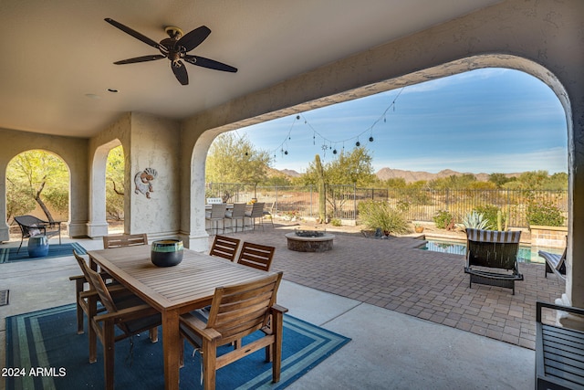 view of patio / terrace with a fire pit, ceiling fan, and a mountain view