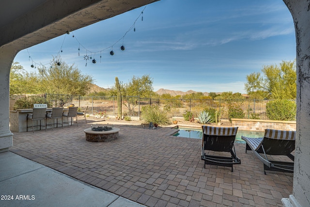 view of patio featuring a mountain view, a fenced in pool, a bar, and an outdoor fire pit