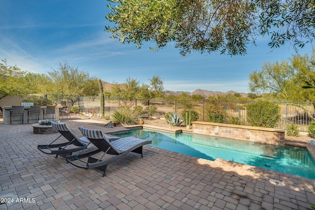 view of swimming pool featuring a mountain view, area for grilling, a patio area, and an outdoor fire pit