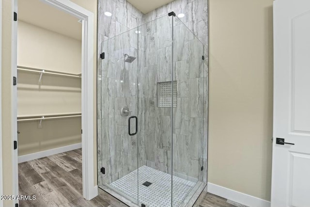1910 E Rainbow Trl, Payson, AZ 85541 - full bathroom featuring a stall shower, a spacious closet, baseboards, and wood finished floors