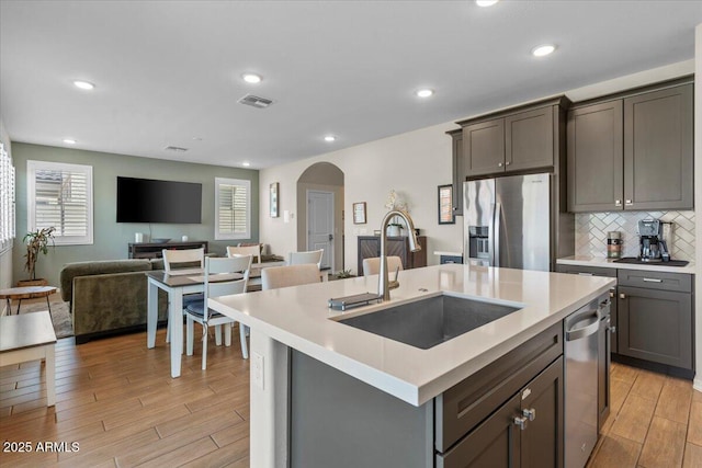 880 S 150th Dr, Goodyear, AZ 85338 - kitchen featuring appliances with stainless steel finishes, light wood finished floors, arched walkways, open floor plan, and light countertops