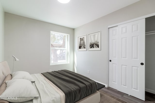 bedroom featuring dark wood finished floors, baseboards, and a closet