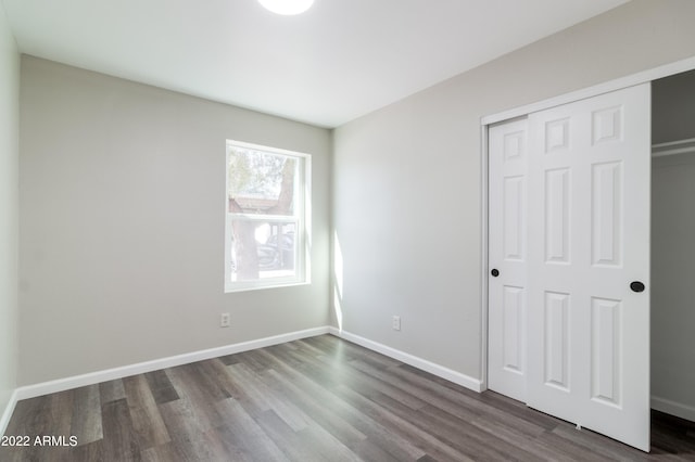 unfurnished bedroom with dark wood-type flooring, baseboards, and a closet