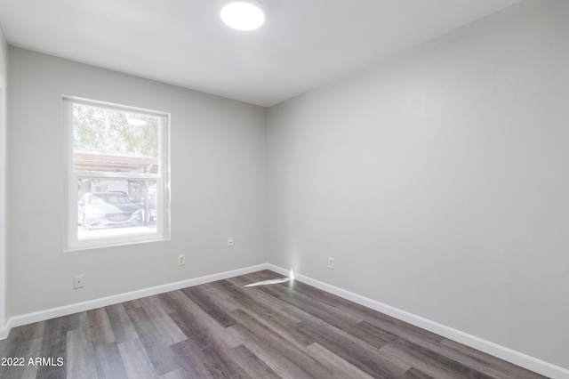 empty room with baseboards and dark wood-type flooring