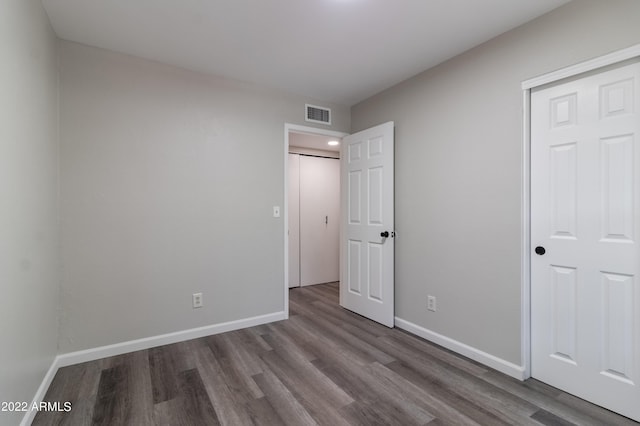 unfurnished bedroom featuring visible vents, baseboards, and wood finished floors
