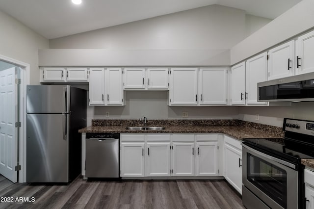 kitchen with vaulted ceiling, white cabinets, appliances with stainless steel finishes, and a sink
