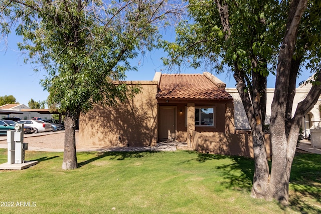 view of front of property featuring stucco siding, a front yard, and a tile roof