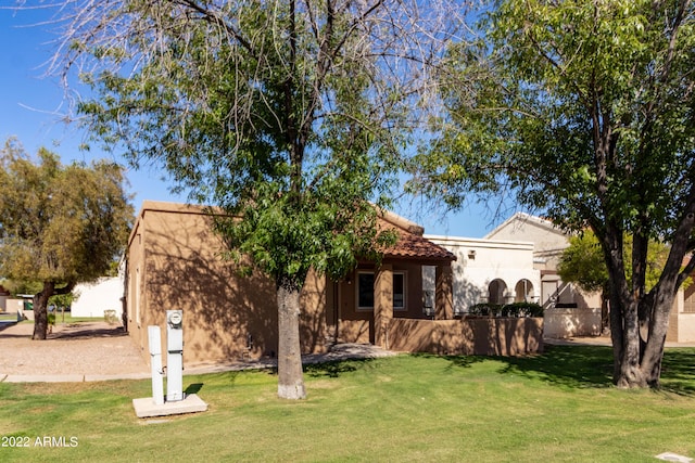 view of front of property with a front yard, a tile roof, and stucco siding