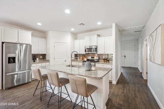 13529 W Remuda Dr, Peoria, AZ 85383 - kitchen with appliances with stainless steel finishes, dark wood-type flooring, tasteful backsplash, a center island with sink, and recessed lighting