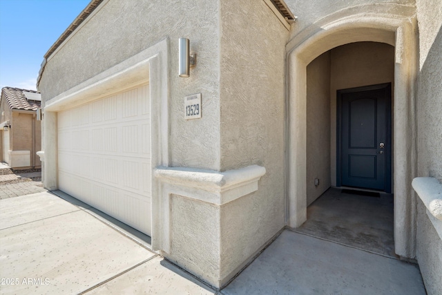 13529 W Remuda Dr, Peoria, AZ 85383 - view of exterior entry featuring stucco siding, a garage, and driveway