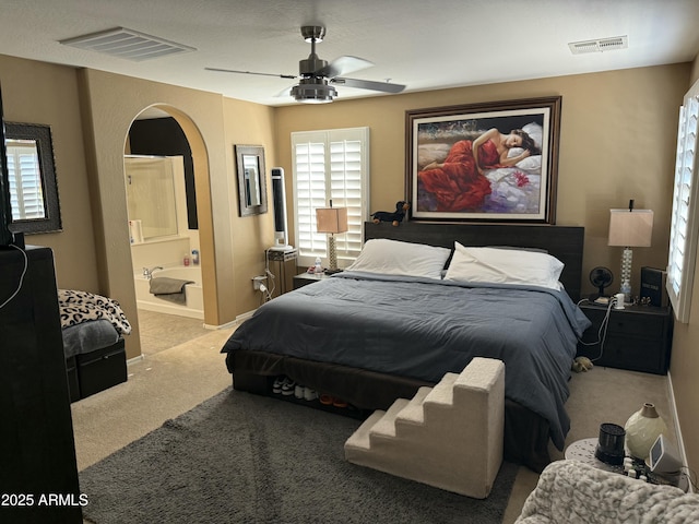 carpeted bedroom with ensuite bath and ceiling fan