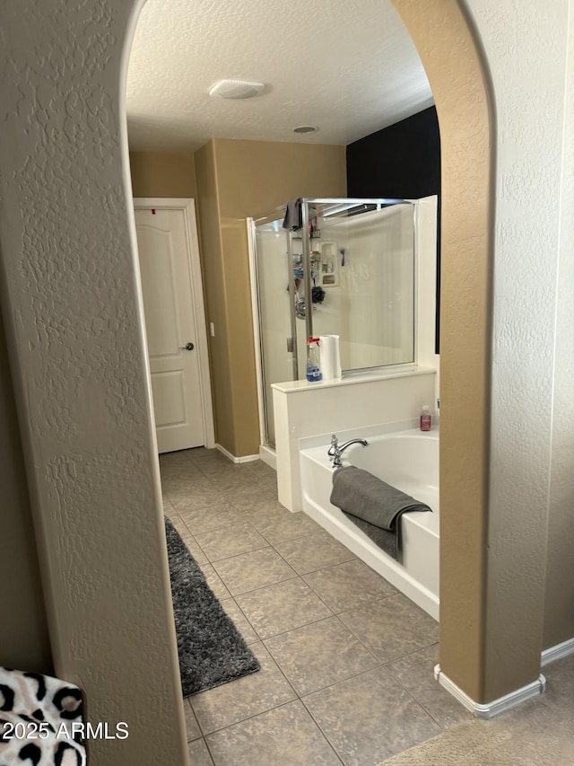 bathroom with tile patterned flooring, separate shower and tub, and a textured ceiling