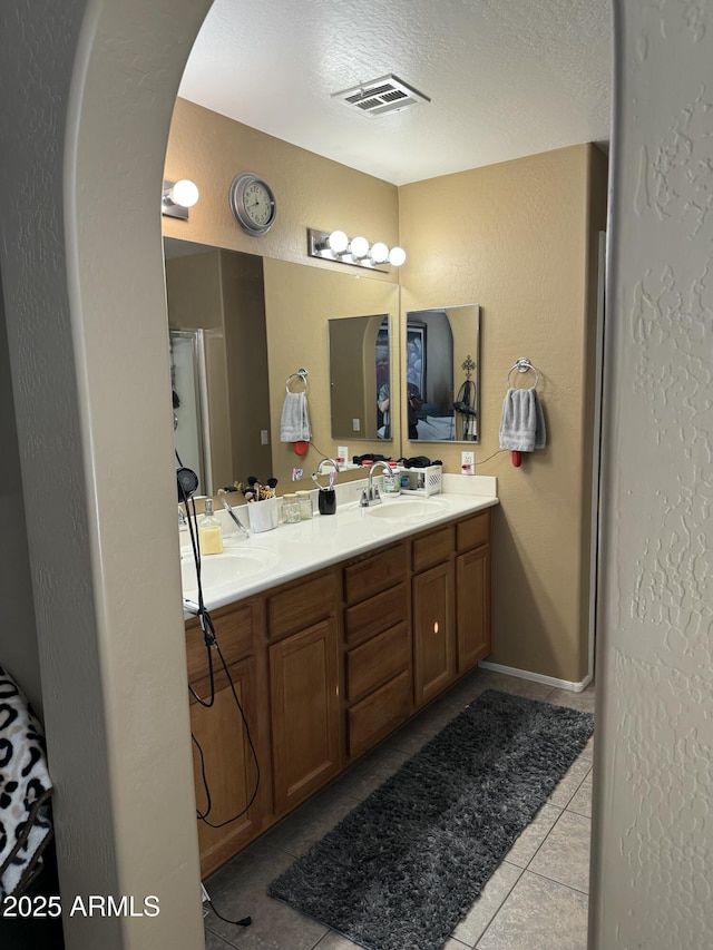 bathroom with tile patterned flooring, vanity, and a textured ceiling