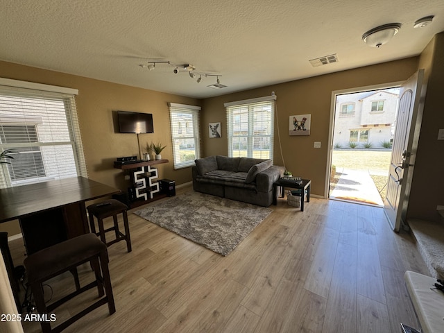 living room featuring track lighting, light hardwood / wood-style floors, and a textured ceiling