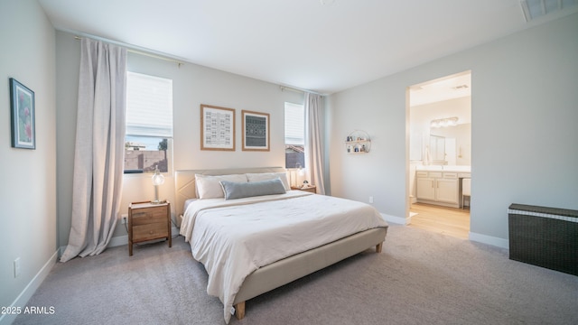 bedroom with visible vents, light carpet, baseboards, and ensuite bathroom