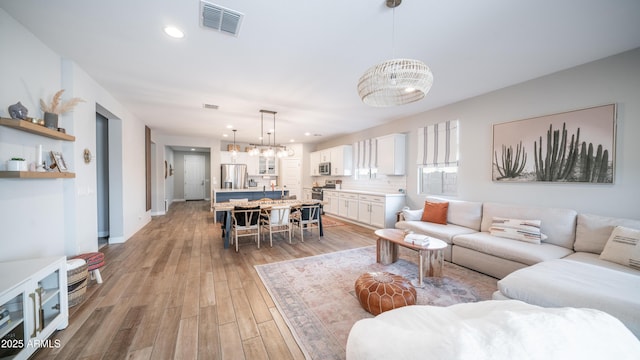 living area with a chandelier, recessed lighting, visible vents, baseboards, and light wood finished floors