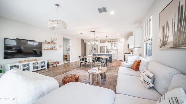 living room with light wood-style floors, baseboards, visible vents, and recessed lighting