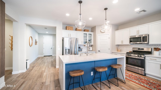 kitchen featuring tasteful backsplash, light countertops, visible vents, appliances with stainless steel finishes, and a sink