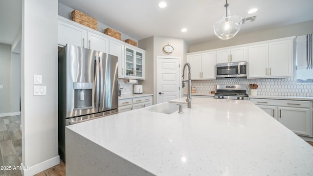 kitchen featuring stainless steel appliances, visible vents, decorative backsplash, white cabinetry, and a sink