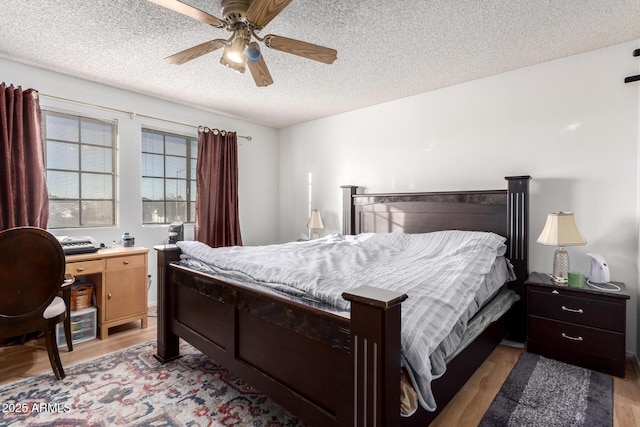 bedroom with hardwood / wood-style flooring, ceiling fan, and a textured ceiling