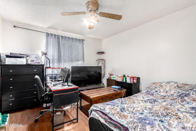 bedroom with hardwood / wood-style flooring, ceiling fan, and a textured ceiling