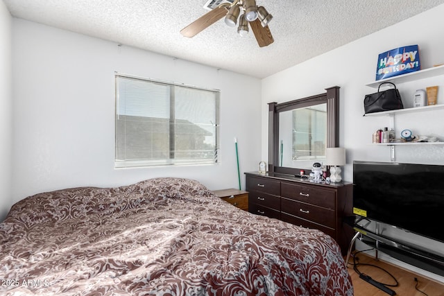 bedroom with ceiling fan, hardwood / wood-style floors, and a textured ceiling