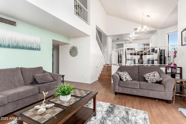 living room featuring wood-type flooring, high vaulted ceiling, and a chandelier