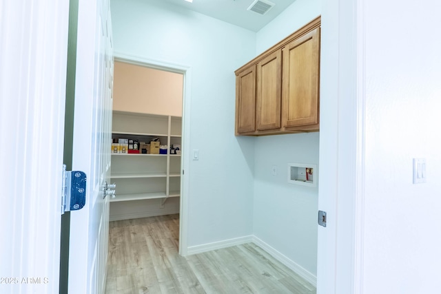 clothes washing area with visible vents, washer hookup, light wood-style flooring, cabinet space, and baseboards