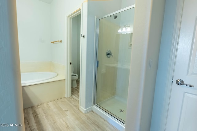 bathroom with a bath, a shower stall, toilet, and wood finished floors