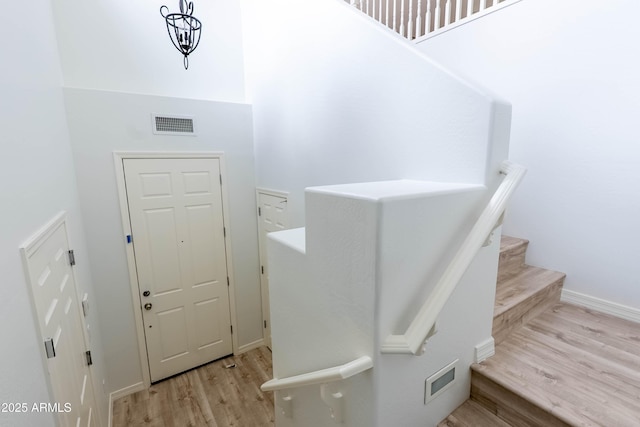 stairway with visible vents, baseboards, and wood finished floors