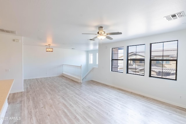 spare room featuring light wood-type flooring, visible vents, and baseboards