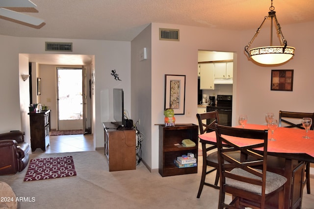 dining area featuring a textured ceiling and light colored carpet