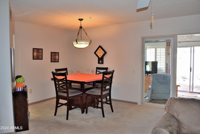 dining area featuring light carpet and a textured ceiling