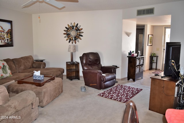 living room featuring ceiling fan, light colored carpet, and a textured ceiling