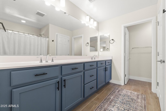 full bathroom with wood finished floors, double vanity, and baseboards