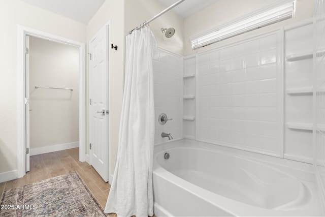 full bath featuring wood finished floors, shower / bath combination with curtain, and baseboards