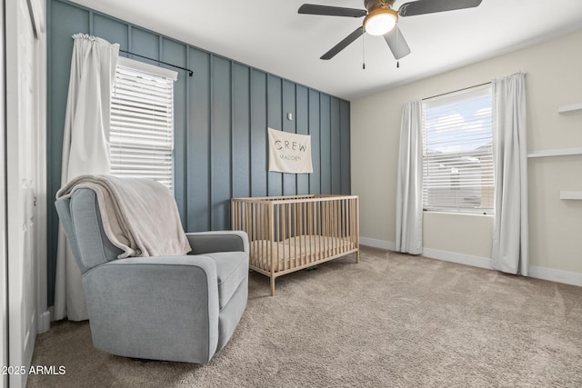 bedroom with carpet flooring, ceiling fan, baseboards, and a crib