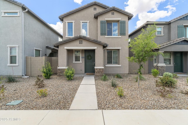 view of front of property with stucco siding, fence, and a tiled roof