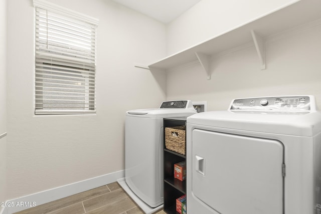 washroom with washing machine and dryer, light wood-style floors, and baseboards